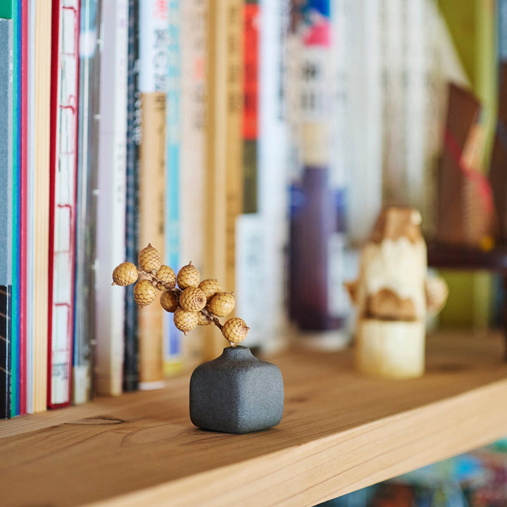 Minimalist dark ceramic bud vase with a square body and soft rounded edges, offering a modern, textured design perfect for small floral accents.
