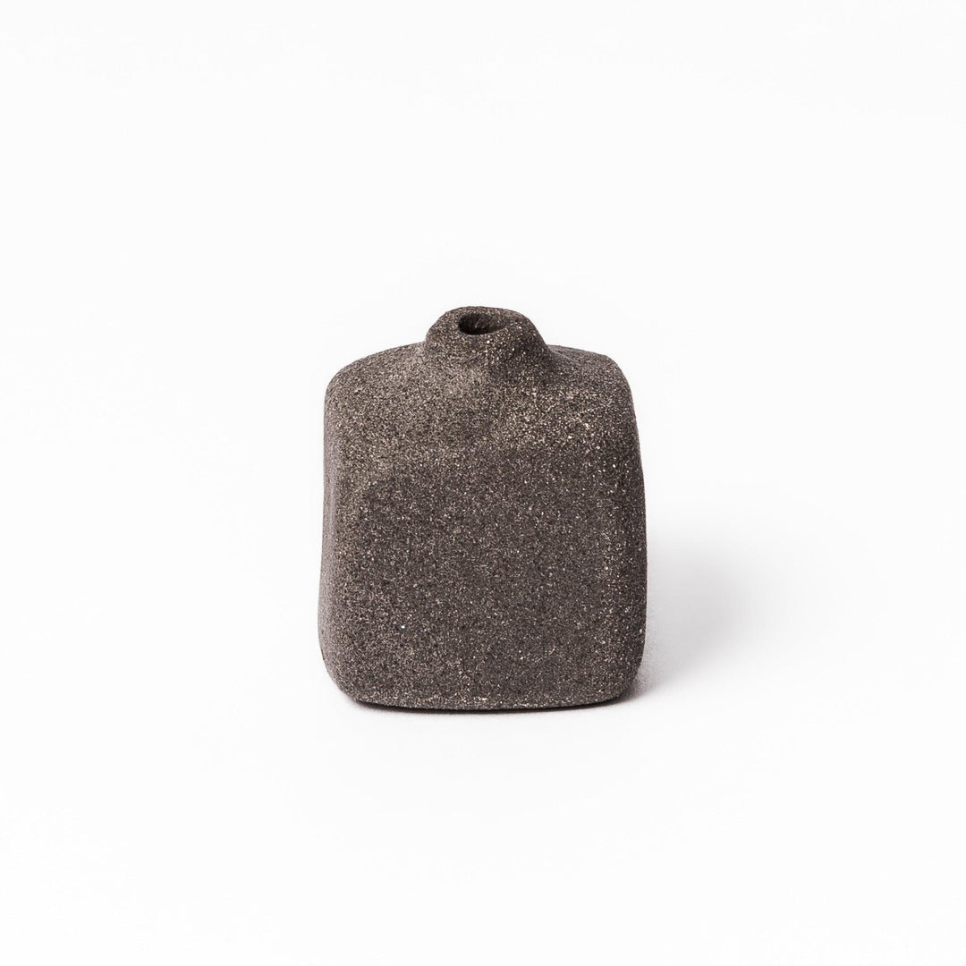 Minimalist dark ceramic bud vase with a square body and soft rounded edges, offering a modern, textured design perfect for small floral accents.