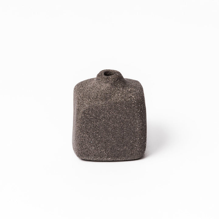Minimalist dark ceramic bud vase with a square body and soft rounded edges, offering a modern, textured design perfect for small floral accents.