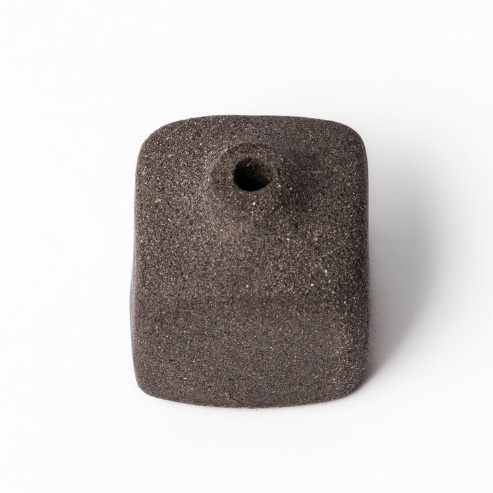 Minimalist dark ceramic bud vase with a square body and soft rounded edges, offering a modern, textured design perfect for small floral accents.