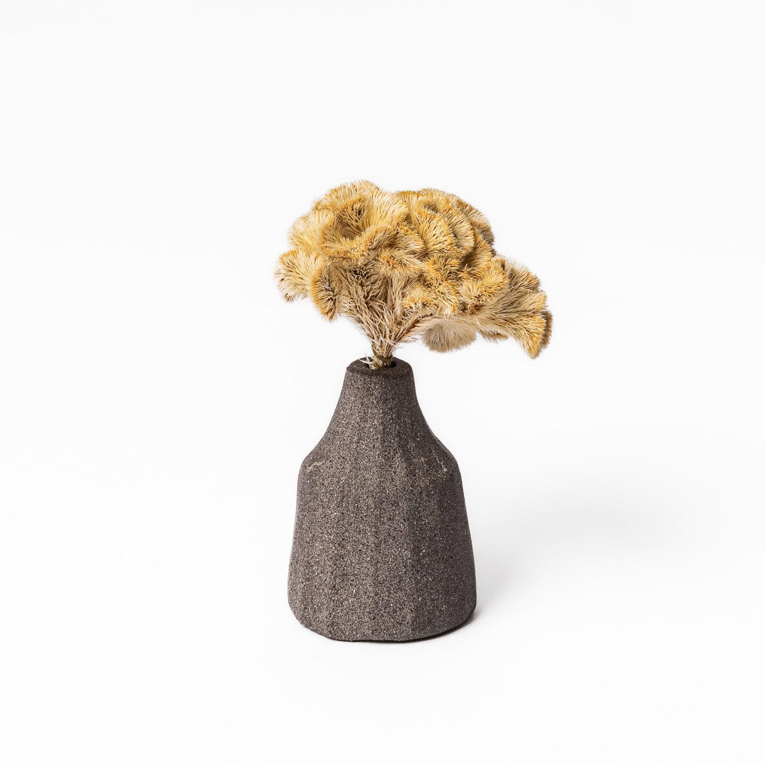 Minimalist dark ceramic bud vase with a faceted prism-like form and matte texture, ideal for adding a sculptural touch to small arrangements.