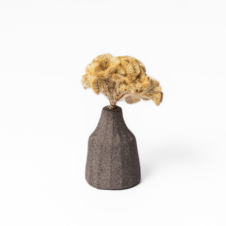 Minimalist dark ceramic bud vase with a faceted prism-like form and matte texture, ideal for adding a sculptural touch to small arrangements.