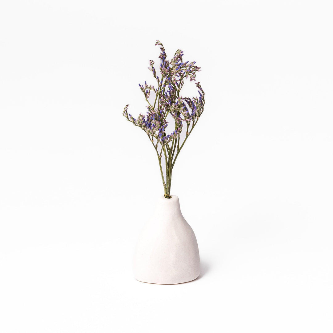 Minimalist white ceramic bud vase with a teardrop shape and narrow opening, ideal for showcasing a single flower in a serene, modern setting.