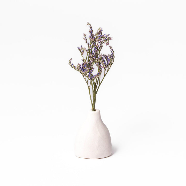 Minimalist white ceramic bud vase with a teardrop shape and narrow opening, ideal for showcasing a single flower in a serene, modern setting.