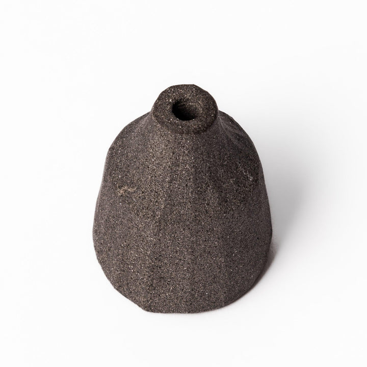 Minimalist dark ceramic bud vase with a faceted prism-like form and matte texture, ideal for adding a sculptural touch to small arrangements.