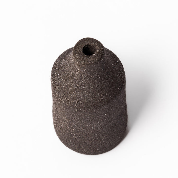 Minimalist dark ceramic bud vase with a cylindrical silhouette and matte finish, perfect for showcasing single stems or dried botanicals.