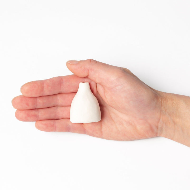 Minimalist white ceramic bud vase with a teardrop shape and narrow opening, ideal for showcasing a single flower in a serene, modern setting.