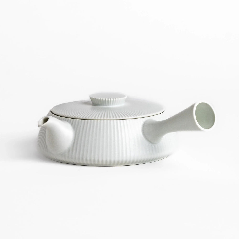 Minimalist ribbed white teapot with sleek spout and round textured lid adding elegance to modern tea sets.
