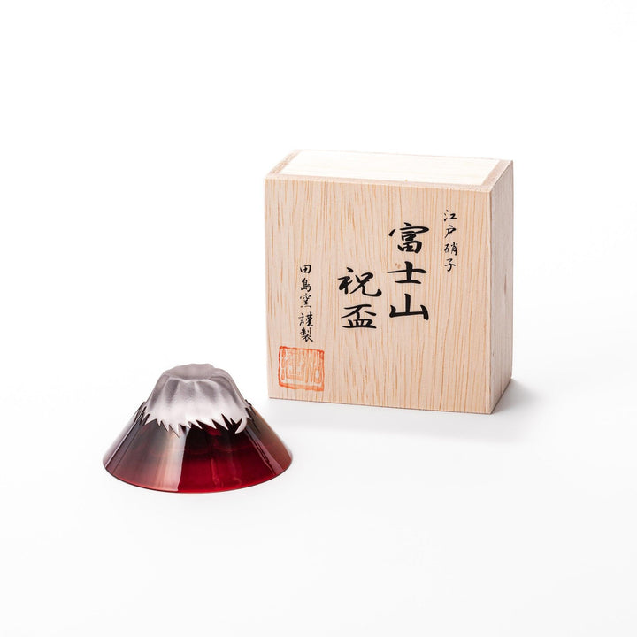 Red glass sake cup in the form of Mount Fuji, complete with a frosted snowcap design, crafted for elegant Japanese-style celebrations.