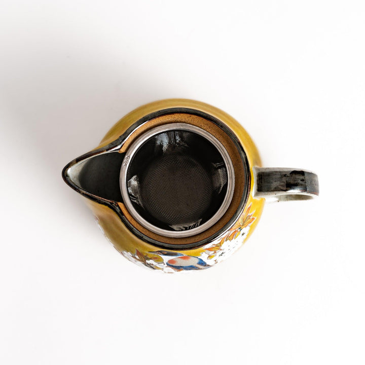 Yellow ceramic teapot with a beautiful bird and flower design, featuring a smooth sheen and secure lid, perfect for serving tea.