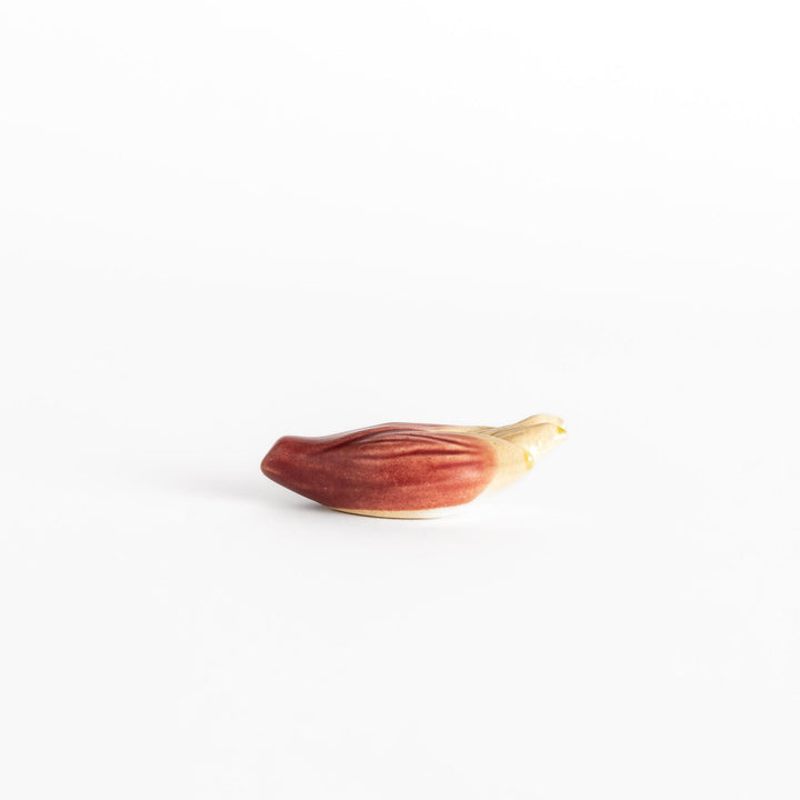 Glossy ceramic myoga ginger-shaped chopstick rest in soft red with beige tones, elegantly crafted for a unique table setting.