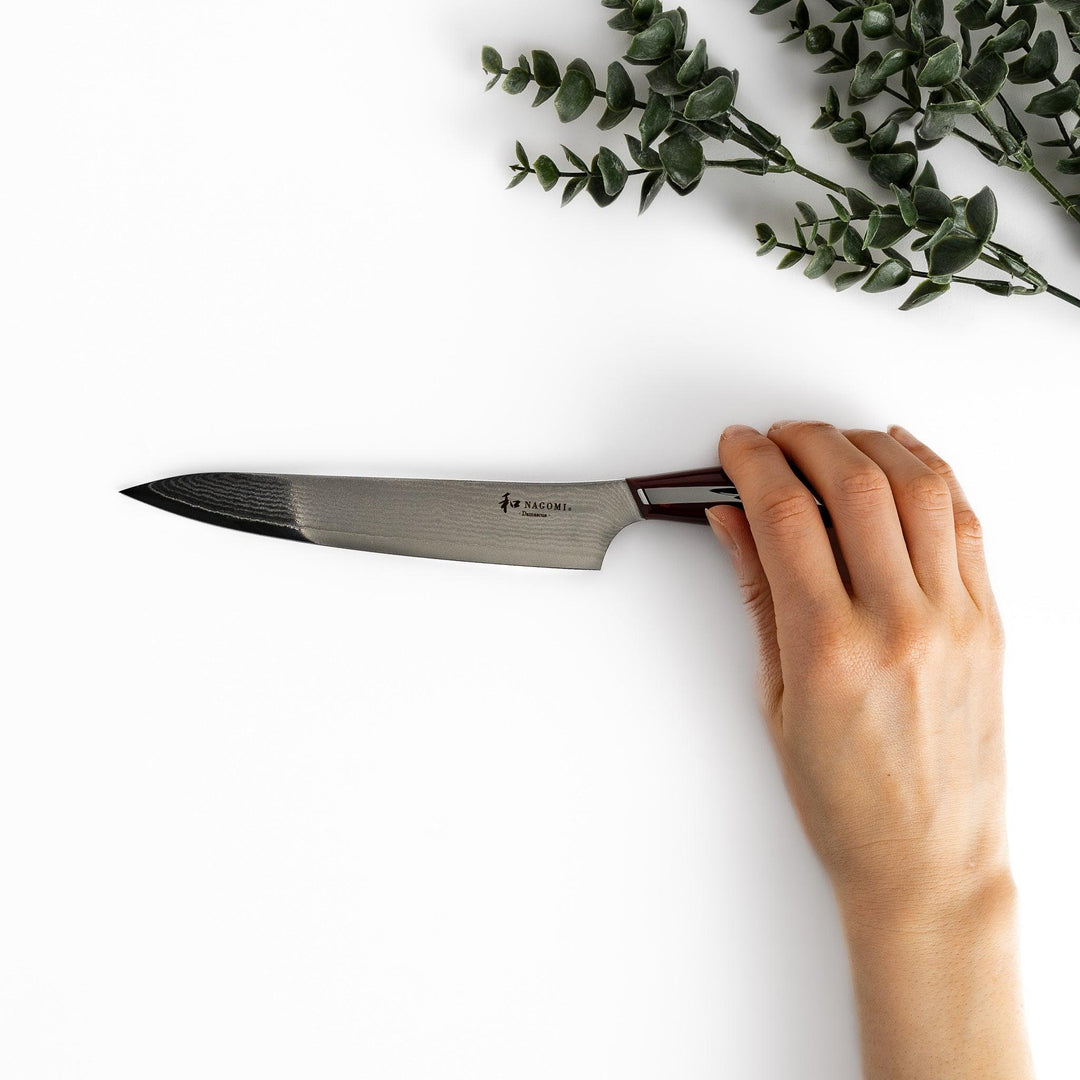 A high-quality Nagomi Damascus utility knife with a beautifully patterned blade and a striped wooden handle, offering excellent precision for everyday kitchen tasks.
