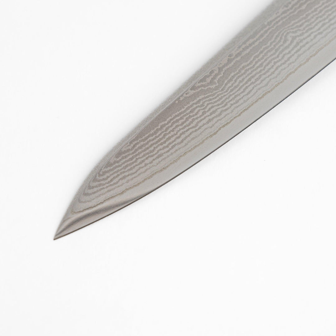 A high-quality Nagomi Damascus utility knife with a beautifully patterned blade and a striped wooden handle, offering excellent precision for everyday kitchen tasks.