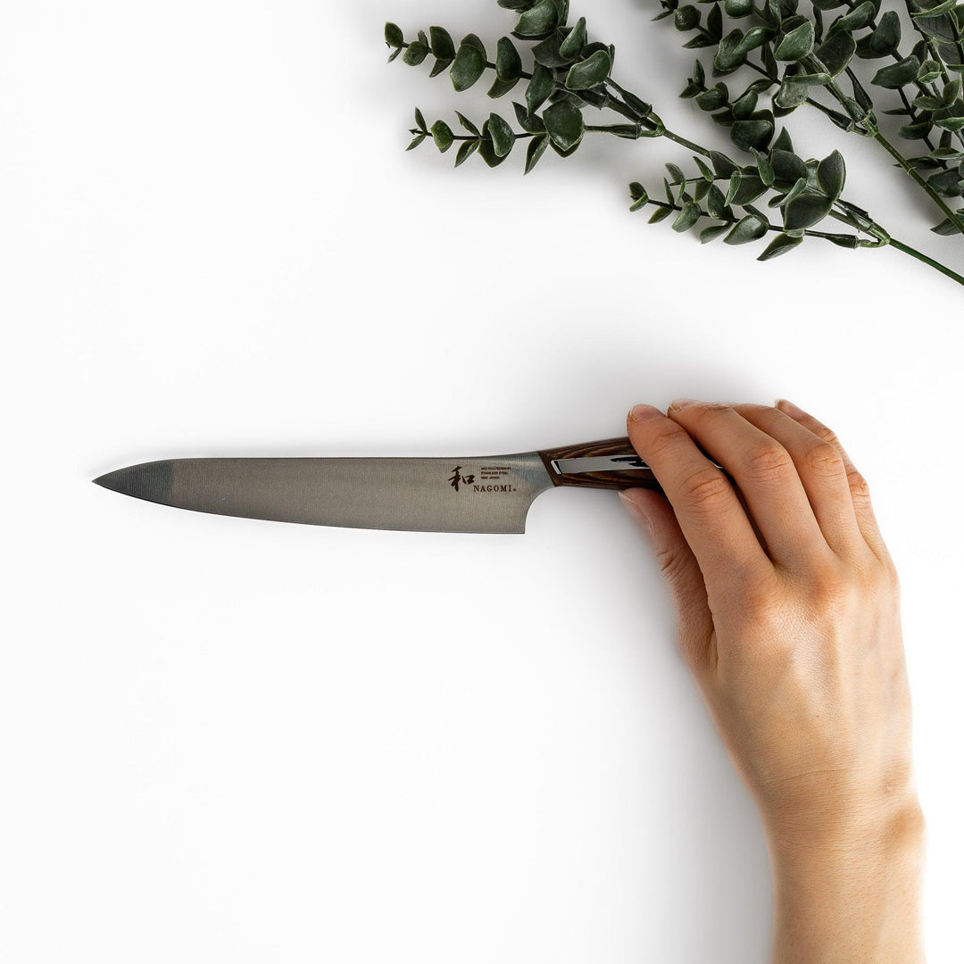 A Nagomi utility knife featuring a sharp, durable blade and a beautifully crafted striped wooden handle, designed for precision and comfort in various kitchen tasks.