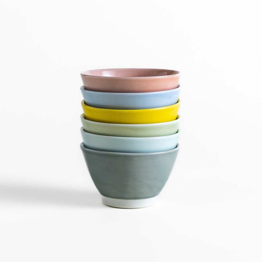 A stack of six pastel-colored dessert bowls in pink, blue, yellow, green, white, and gray, each with a smooth finish, perfect for adding a soft touch to your table setting.