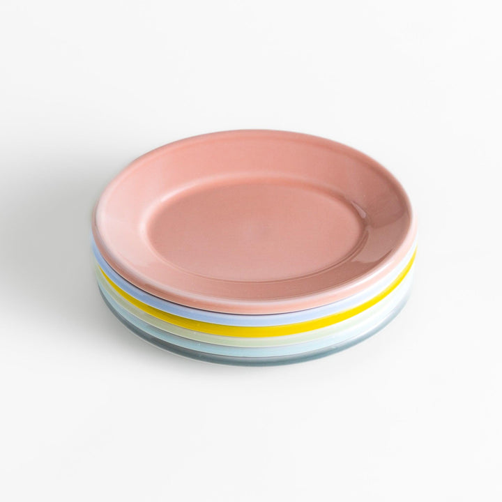 A stack of six pastel-colored oval dessert plates in pink, blue, yellow, green, white, and gray, each with a smooth, glossy finish, perfect for adding a soft, serene touch to your table setting.