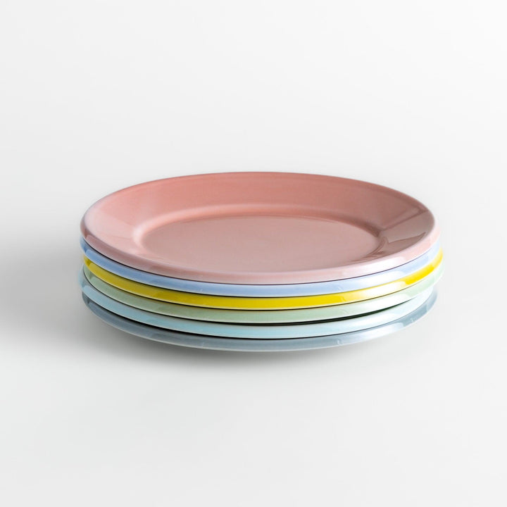 A stack of six pastel-colored oval salad plates in pink, blue, yellow, green, white, and gray, each with a smooth, glossy finish, perfect for adding a soft, serene touch to your table setting.