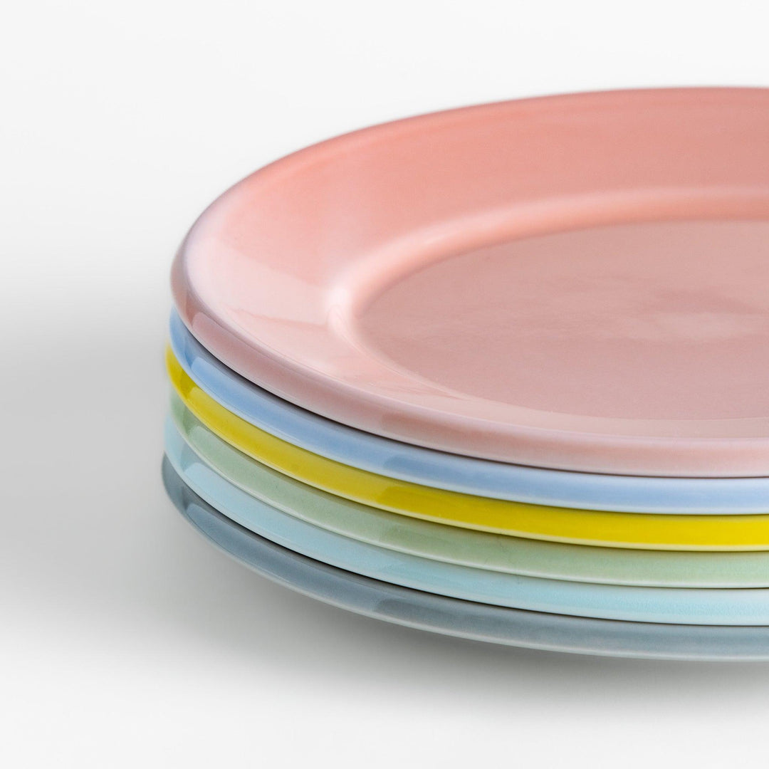 A stack of six pastel-colored oval salad plates in pink, blue, yellow, green, white, and gray, each with a smooth, glossy finish, perfect for adding a soft, serene touch to your table setting.