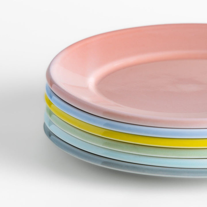 A stack of six pastel-colored oval salad plates in pink, blue, yellow, green, white, and gray, each with a smooth, glossy finish, perfect for adding a soft, serene touch to your table setting.