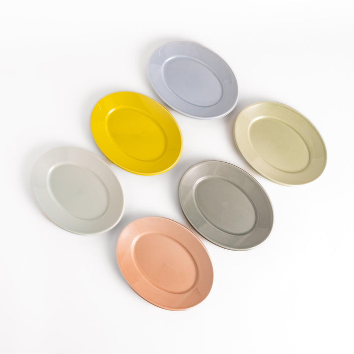 Six pastel-colored oval salad plates in pink, blue, yellow, green, white, and gray, each with a smooth, glossy finish, perfect for adding a soft, serene touch to your table setting.