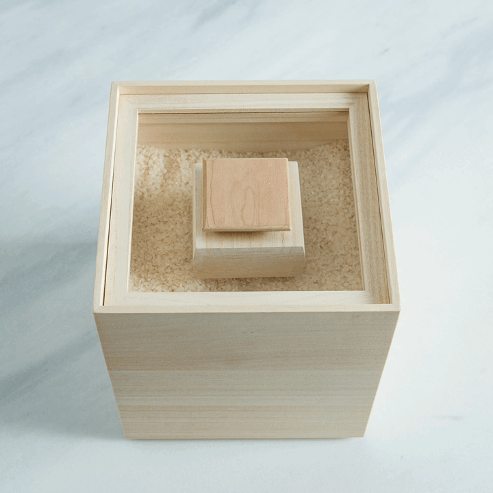 Paulownia wood rice container with inner lid, filled with rice for traditional Japanese kitchen storage.