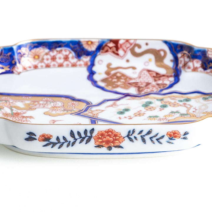 A rectangular salad plate with handles, decorated with scenes of cranes and trees in a traditional Japanese style, bordered by intricate red, blue, and gold patterns.