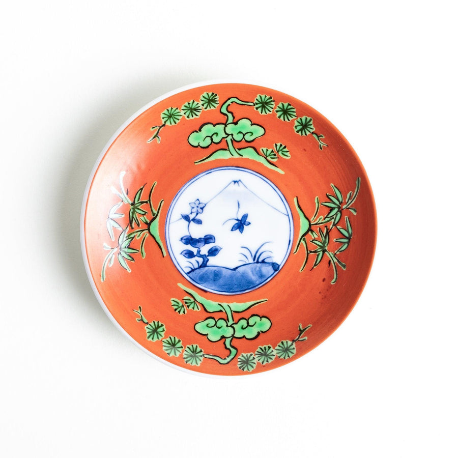 Round plate with an orange background, green leaves, and a Mount Fuji scene.