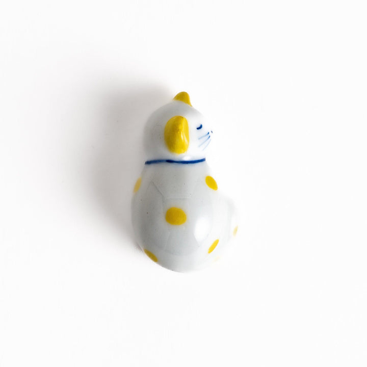 Adorable white ceramic chopstick rest shaped like a sleeping cat with yellow dots, adding a cheerful touch to your dining experience.