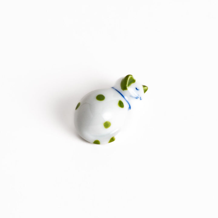 Charming white ceramic chopstick rest shaped like a sleeping cat with green dots, bringing a touch of nature to your table setting.