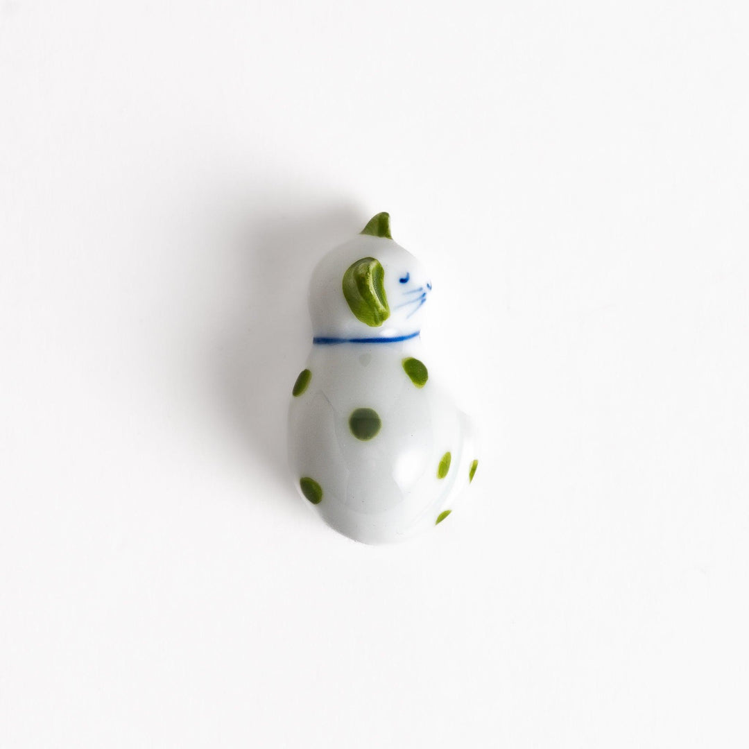 Charming white ceramic chopstick rest shaped like a sleeping cat with green dots, bringing a touch of nature to your table setting.