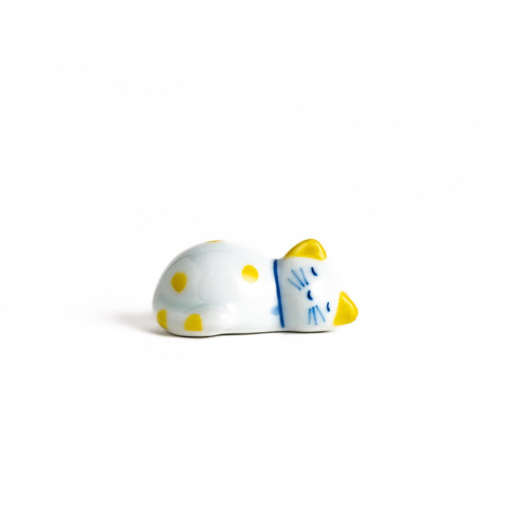 Adorable white ceramic chopstick rest shaped like a sleeping cat with yellow dots, adding a cheerful touch to your dining experience.