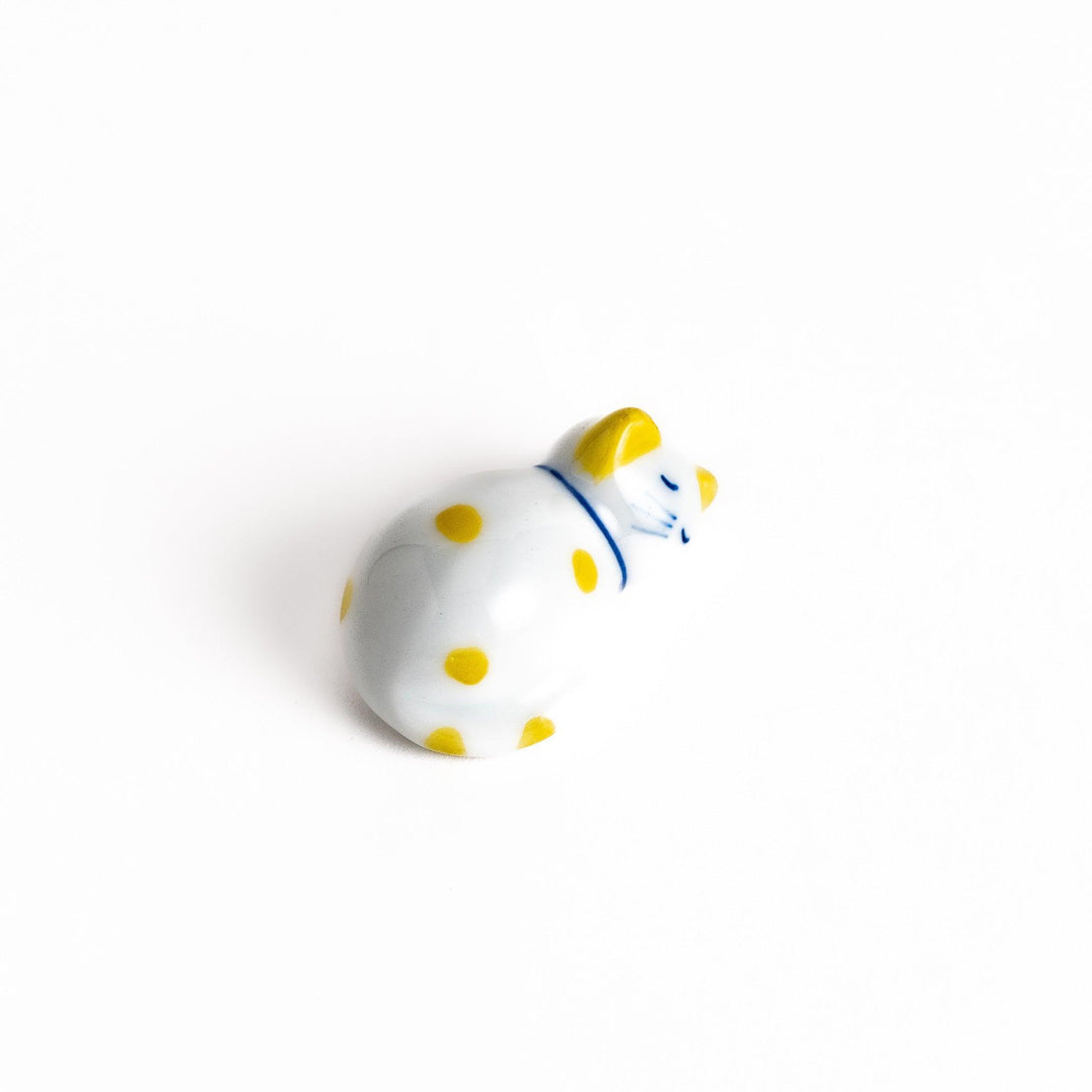 Adorable white ceramic chopstick rest shaped like a sleeping cat with yellow dots, adding a cheerful touch to your dining experience.