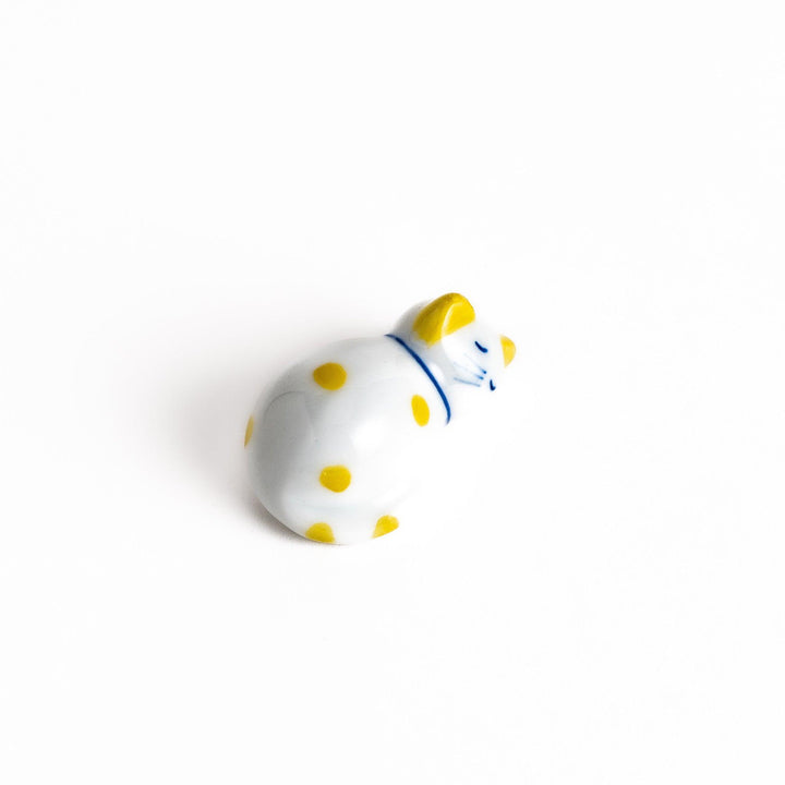 Adorable white ceramic chopstick rest shaped like a sleeping cat with yellow dots, adding a cheerful touch to your dining experience.