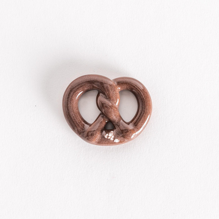 A ceramic pretzel-shaped chopsticks rest with a brown glaze.