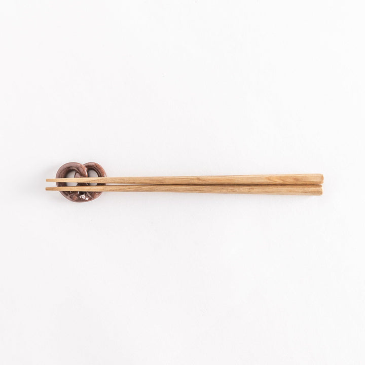 Full view of chopsticks placed on the pretzel-shaped rest.