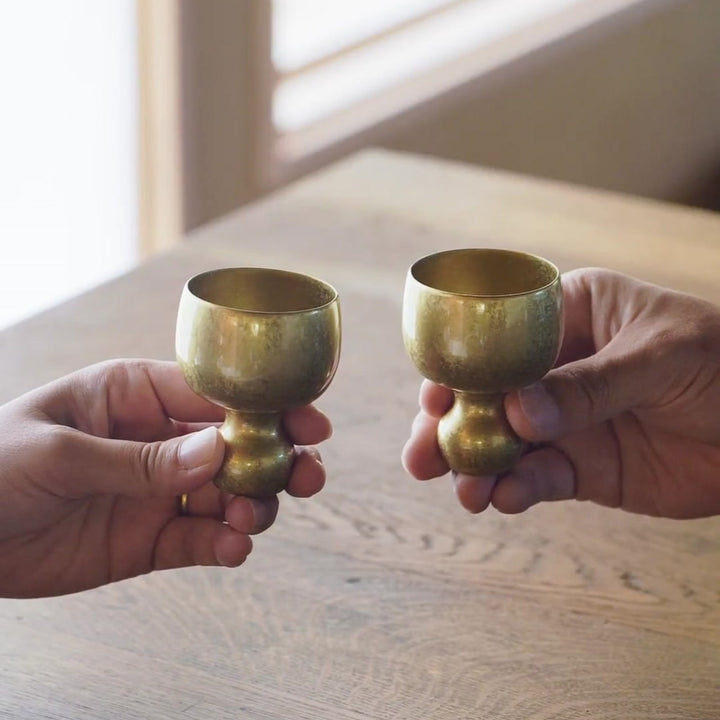 Two brass sake cups produce a clear chime when clinked, also used as meditation bowls by striking or rubbing the rim.