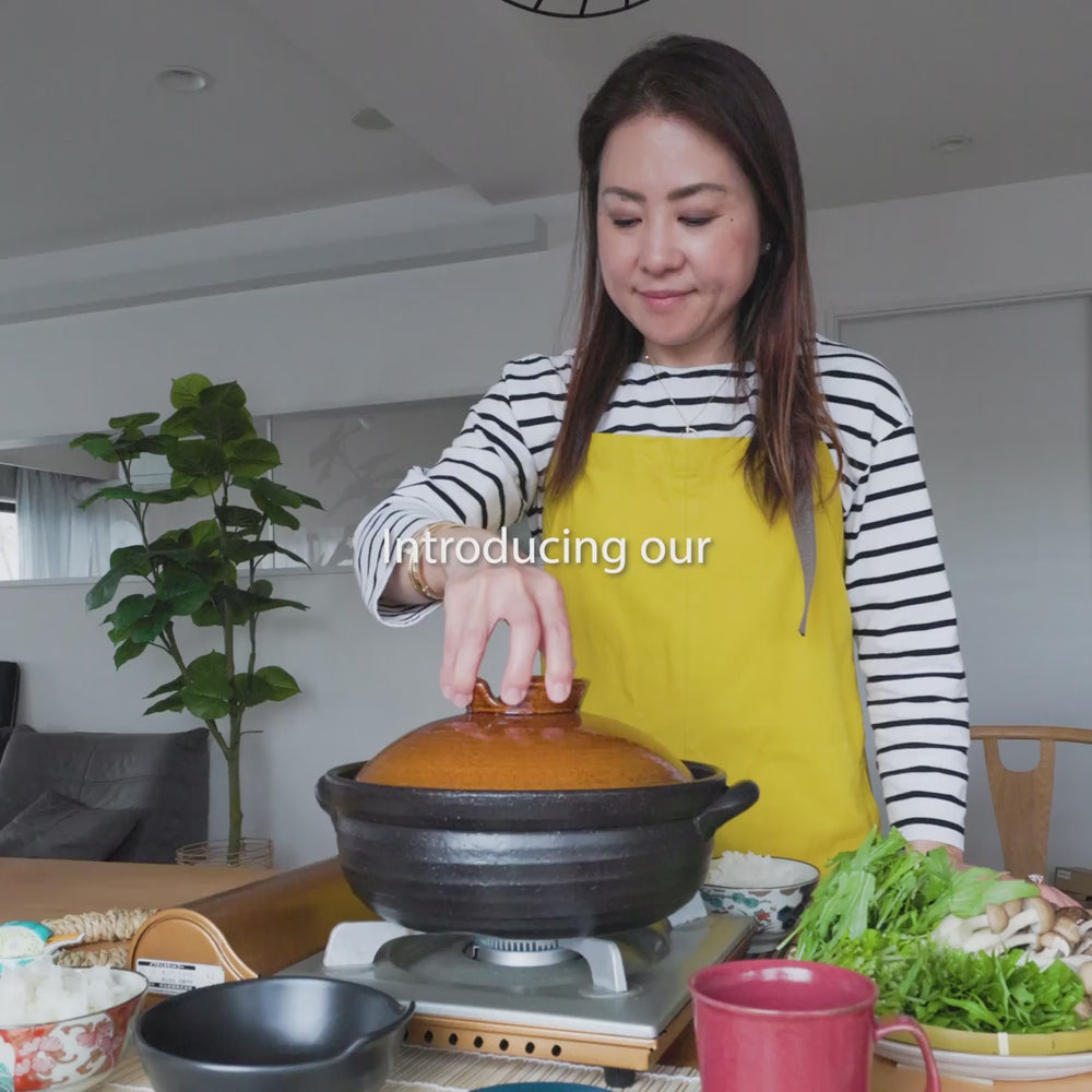 Cooking hot pot with a rustic glaze japanese donabe clay pot compatible with induction cooktop adding fresh vegetables