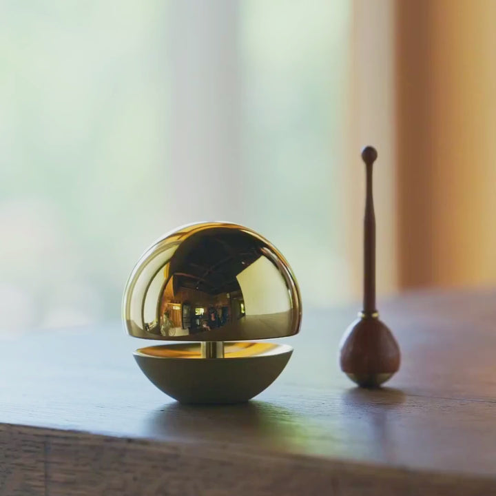 Japanese meditation prayer chime gently struck producing a clear calming tone in a minimalist setting