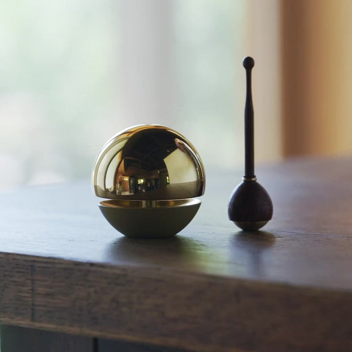 A small Japanese brass meditation chime, producing clear and soothing tones when gently struck with a stick.