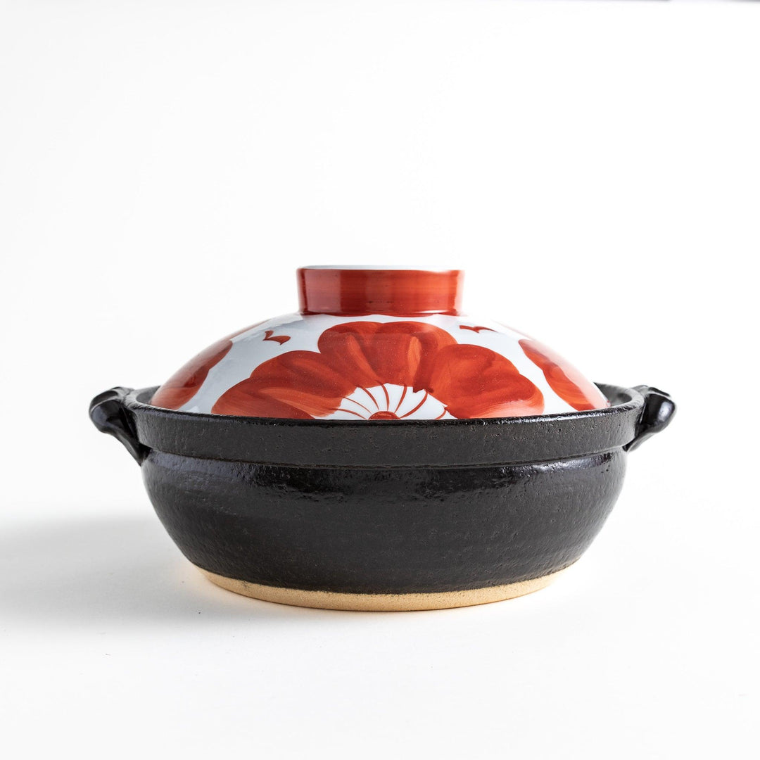 Side profile of the donabe, highlighting its sturdy black base and vibrant floral lid, a striking piece for your table.