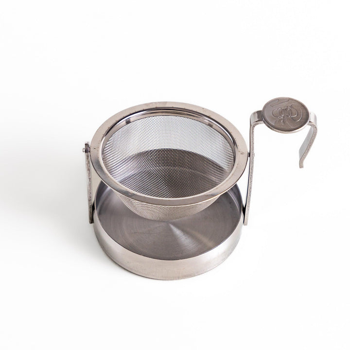 Stainless steel rotating tea strainer with fine mesh and drip tray, designed for effortless loose-leaf tea brewing and easy cleanup.