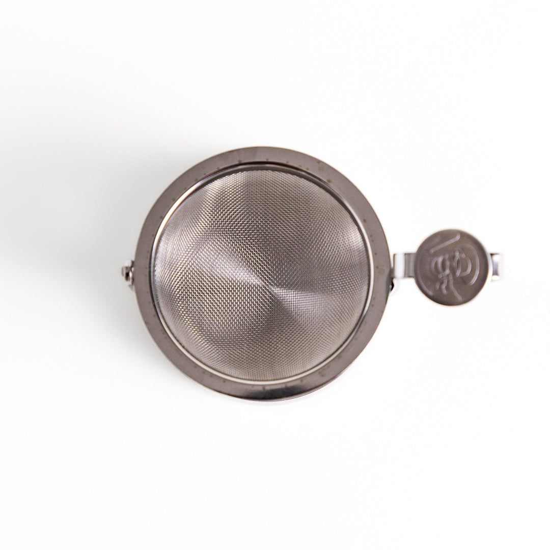 Stainless steel rotating tea strainer with fine mesh and drip tray, designed for effortless loose-leaf tea brewing and easy cleanup.
