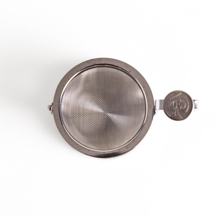 Stainless steel rotating tea strainer with fine mesh and drip tray, designed for effortless loose-leaf tea brewing and easy cleanup.