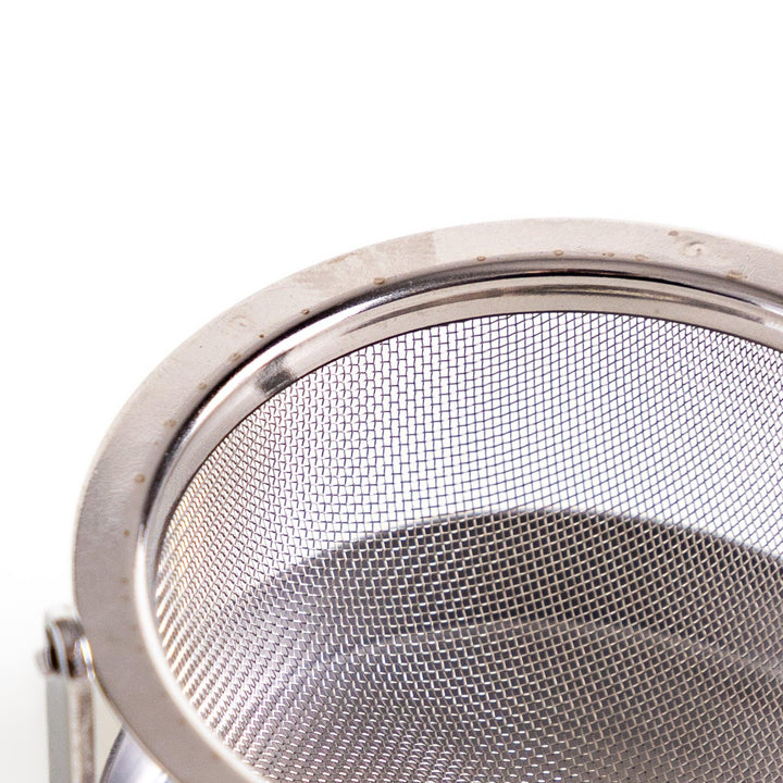 Stainless steel rotating tea strainer with fine mesh and drip tray, designed for effortless loose-leaf tea brewing and easy cleanup.