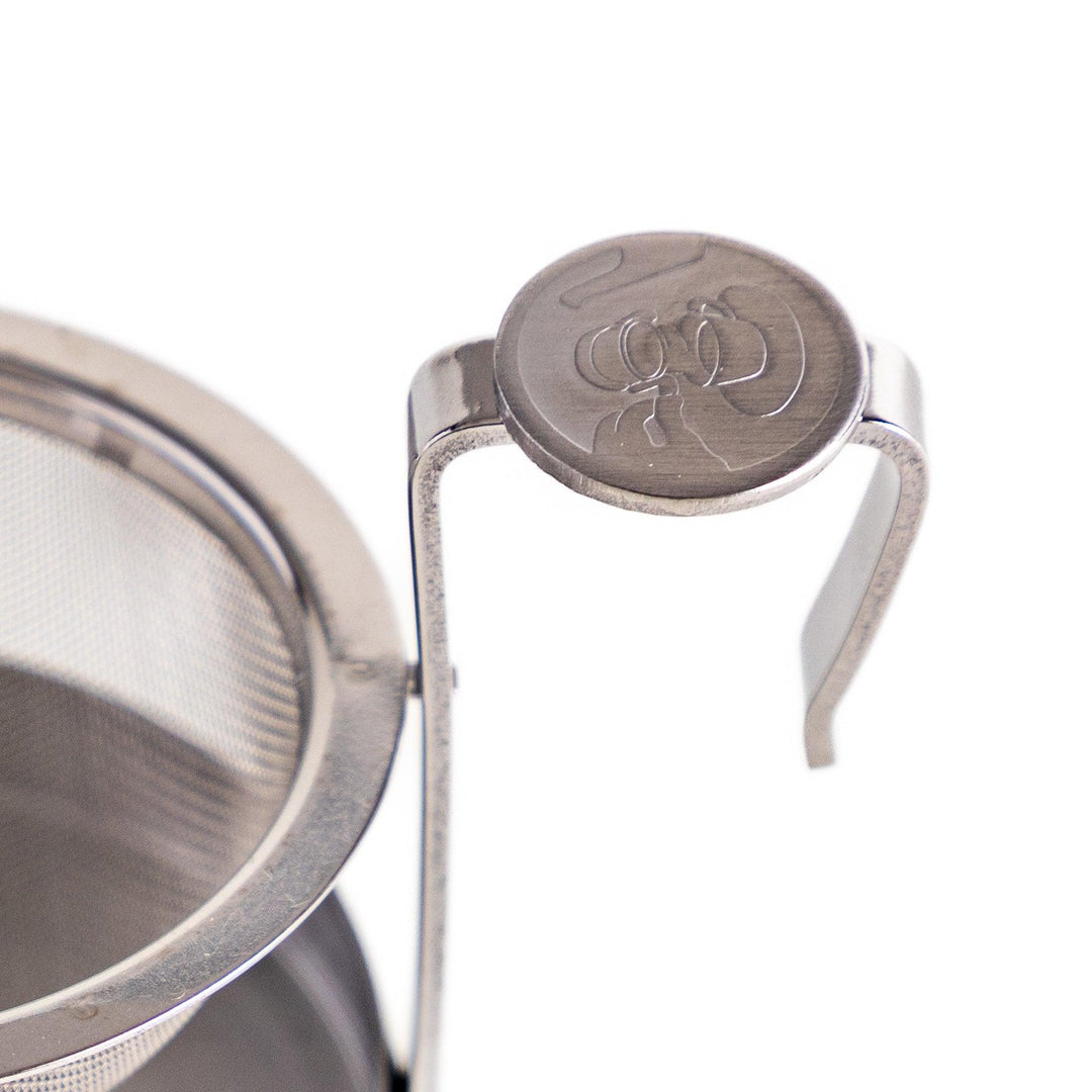 Stainless steel rotating tea strainer with fine mesh and drip tray, designed for effortless loose-leaf tea brewing and easy cleanup.