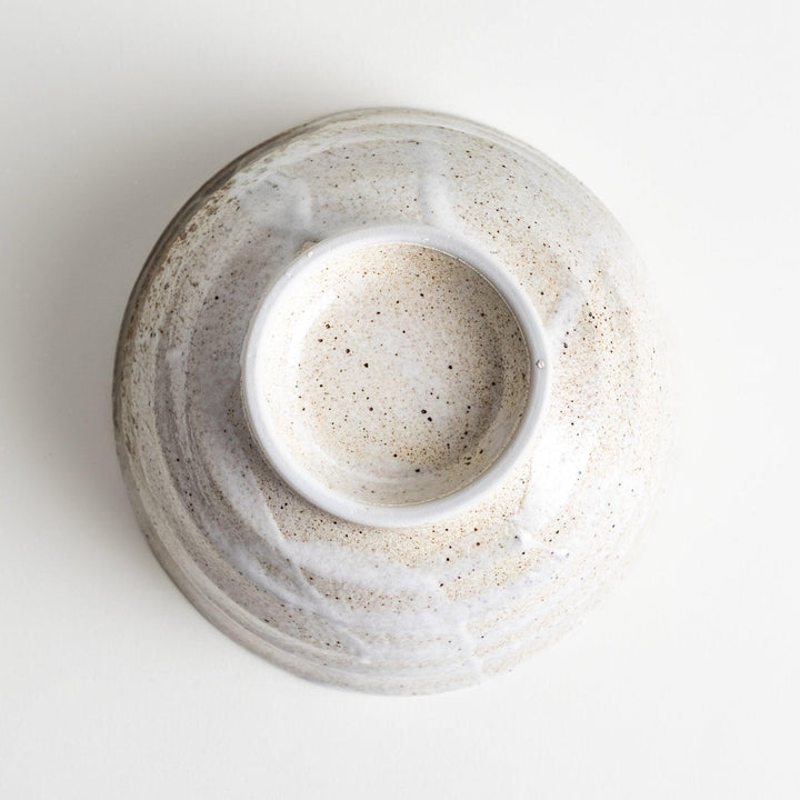 A ceramic bowl with a speckled cream and brown glaze, showcasing an earthy and organic finish.