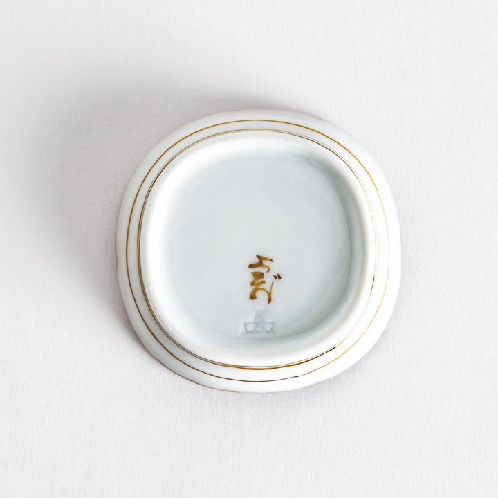 Close-up view of the interior of a small oval sauce dish, highlighting its smooth surface and brown dotted rim.