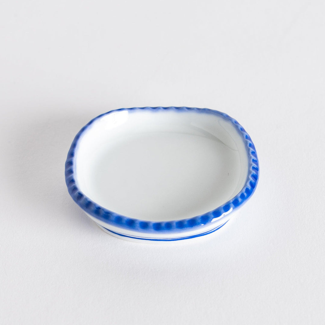Angle view of the oval sauce dish displaying the subtle curvature and rustic finish.