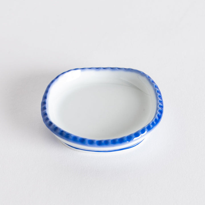 Angle view of the oval sauce dish displaying the subtle curvature and rustic finish.