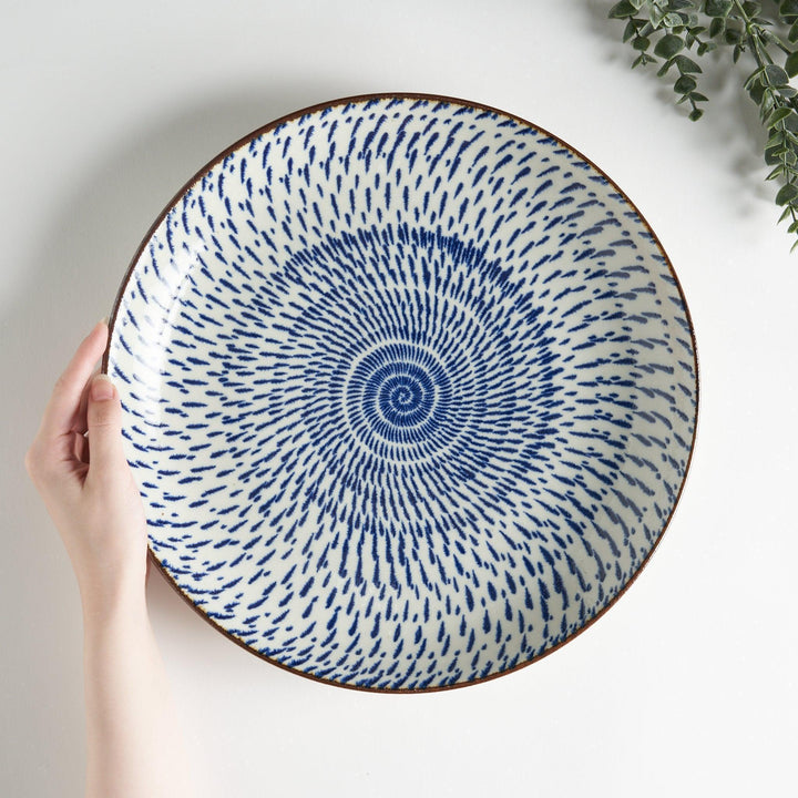 A round serving plate featuring a striking blue radial burst design from the center.
